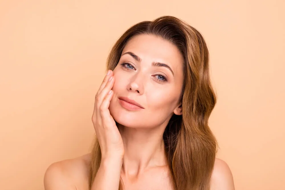 Serum dropper held above an open palm against a soft neutral background